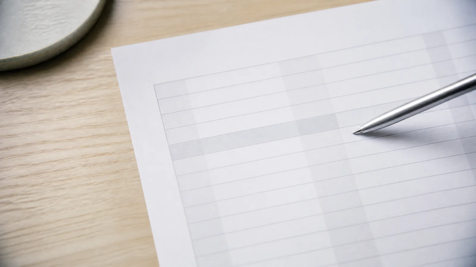 A close-up of a working paper with one row highlighted and a pen resting near it